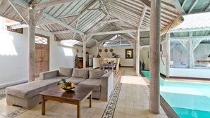 A spacious living area with a large sofa, a coffee table with fruit, and a pool visible in the background. - At Last, Rent Your Own 5 Star Private Villa in Seminyak at an Affordable Rate, Bali Villa 1145 (Bali)