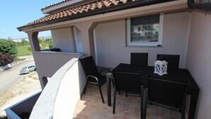 Un balcon avec une table et des chaises, une fenêtre et une vue sur la rue.