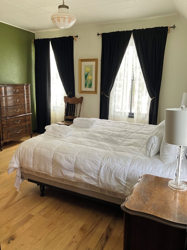 Une chambre à coucher avec un grand lit, une commode en bois, une chaise et une lampe.