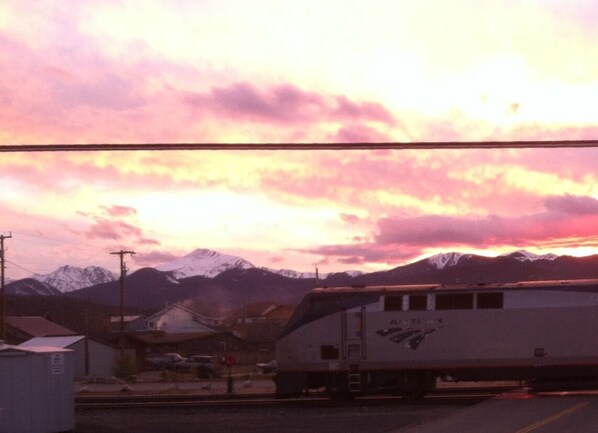 A train with 'AMTRAK' written on it, parked in a station with mountains in the background.