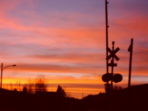A silhouette of a railroad crossing sign against a sunset sky.
