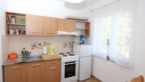 A compact kitchen with wooden cabinets, a stove, a sink, and a refrigerator. - GABRIEL One-Bedroom Apartment 3 (Rovinj)