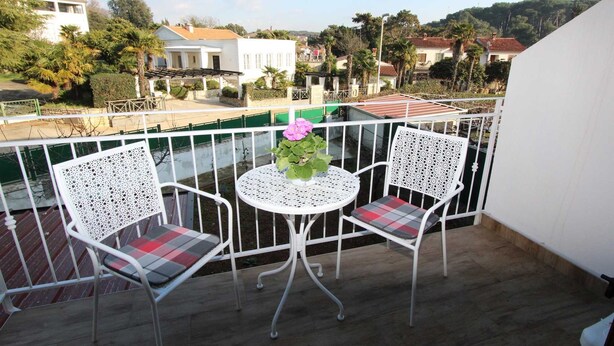 A balcony with two white chairs and a small table, overlooking a residential area with houses and greenery. - GABRIEL One-Bedroom Apartment 3 (Rovinj)
