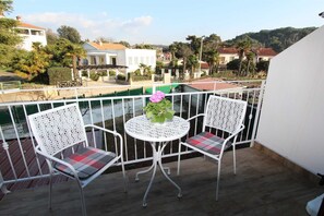 A balcony with two white chairs and a small table, overlooking a residential area with houses and greenery. - GABRIEL One-Bedroom Apartment 3 (Rovinj)