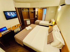 A hotel room with a bed, a desk with a laptop, a television, and a wardrobe. - Lummina Hotel (Barueri)