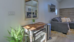 A living room with a grey sofa, a wooden table with a mirror, and a potted fern. - A Night with the Alpacas & Alpaca Experience! (Silt)