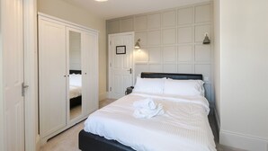 A bedroom with a large bed, a wardrobe, a mirror, and a ceiling light. - The William IV (London)