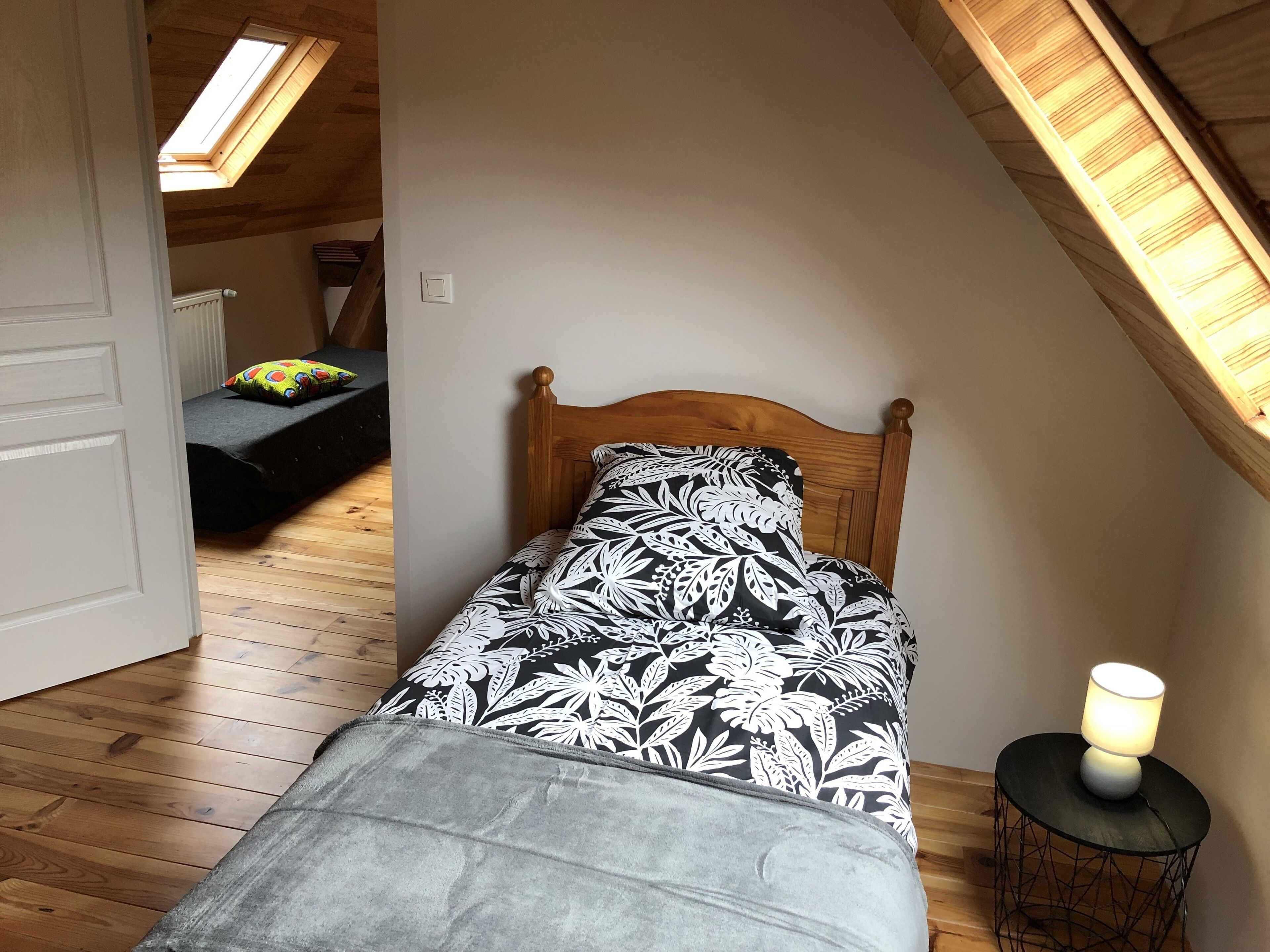 Ein kleines, gemütliches Schlafzimmer mit einem hölzernen Bett, einem Oberlicht und einer Nachttischlampe.