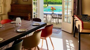 A dining area with a table set for four, a piano, and a view of an outdoor pool area. - Villandry - Domaine de L'augeonnière (Savonnieres)