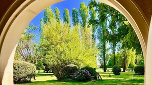 An arched doorway leading to a well-maintained garden with a variety of trees and shrubs. - Villandry - Domaine de L'augeonnière (Savonnieres)