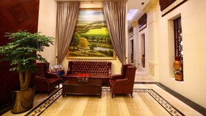 A luxurious lobby with a large painting, leather furniture, and a potted plant. - Inner Mongolia Hotel Forbidden City (Beijing)