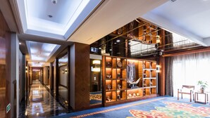 A hotel lobby with a patterned carpet, a reception desk, and a display of decorative items. - Inner Mongolia Hotel Forbidden City (Beijing)