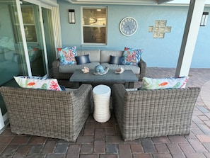 A patio area with a wicker sofa set, a table, and decorative pillows. - NEWLY RENOVATED!!! Anna Maria Island - Key Royale - Dock/Lift - Heated Pool/Spa (Holmes Beach)