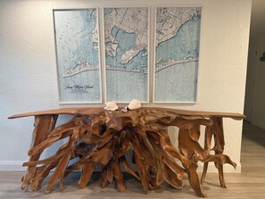 Una mesa de madera con un diseño único, ubicada frente a una pared con tres mapas enmarcados.
