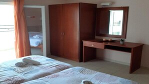 Ein Schlafzimmer mit einem Bett, einem Kleiderschrank, einem Schreibtisch und einem Spiegel.