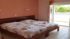 Ein Schlafzimmer mit einem großen Bett, einem Nachttisch, einem Fenster mit Vorhängen und Blick ins Freie.