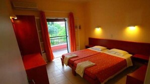 Ein Hotelzimmer mit einem Bett, einem Kleiderschrank und einem Balkon mit roten Vorhängen.