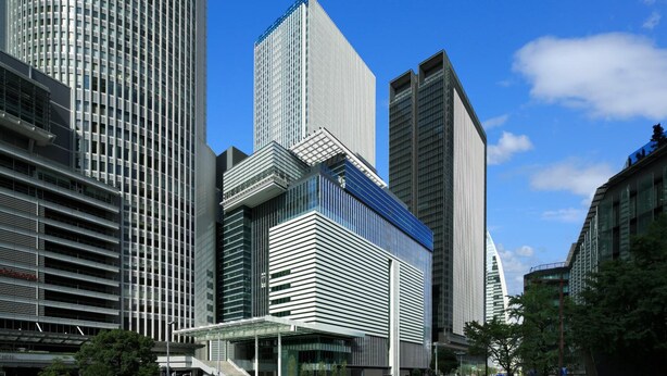 A modern urban skyline with high-rise buildings, including a prominent rectangular skyscraper with a unique top section.