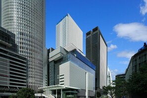 A modern urban skyline with high-rise buildings, including a prominent rectangular skyscraper with a unique top section.