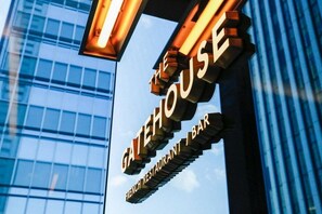 A sign for 'The Gatehouse French Restaurant Bar' with a modern glass building in the background.