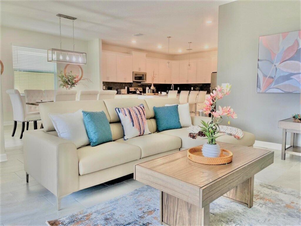 A modern living room with a beige sofa, a wooden coffee table, and a kitchen in the background.