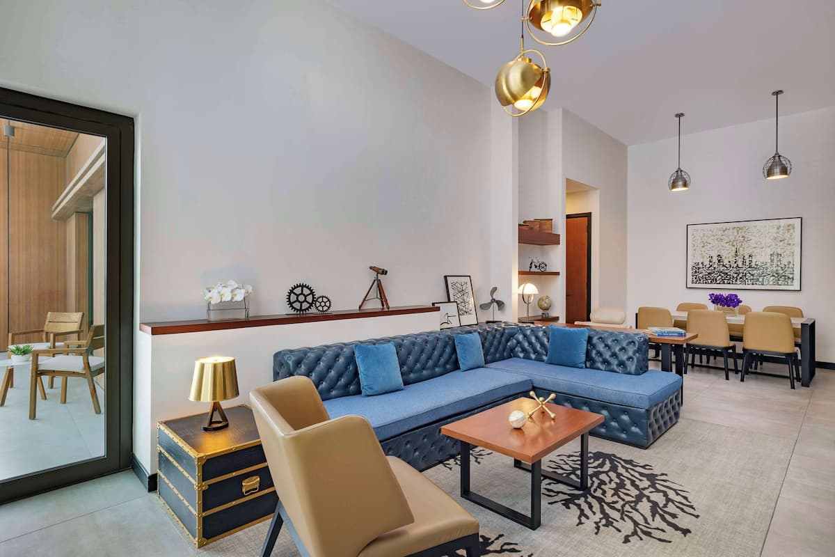 A modern living room with a sectional sofa, a coffee table, and a dining area with chairs and a table.