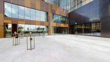 A spacious outdoor area with modern architecture, large glass windows, and a tiled floor.