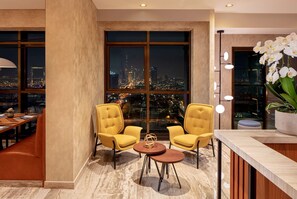 A modern hotel room with a large window offering a city view, two yellow armchairs, a small round table, and a potted orchid. - DoubleTree by Hilton Dubai M Square Hotel & Residences (Dubai)