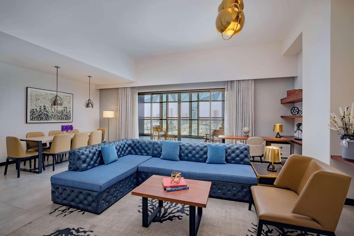 A modern living room with a sectional sofa, a coffee table, and a dining area with chairs and a table.