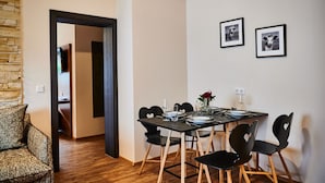 A dining area with a table set for four, black chairs, and two framed pictures on the wall. - EVI APARTMENTS - Heike (Kaprun)