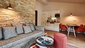 Een moderne woonkamer met een stenen muur, een bank, een ronde salontafel en een eethoek met rode stoelen.