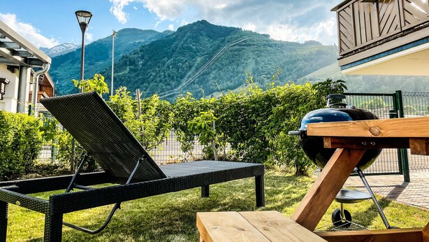 Een terras met een barbecue, een stoel en uitzicht op bergen.
