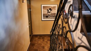 Een trap met een metalen leuning, een lijst met een foto van een koe aan de muur, en een deur aan de bovenkant.