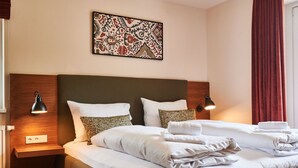 Ein Hotelzimmer mit einem großen Bett, zwei Nachttischlampen, einem Wandbild und einem roten Vorhang.