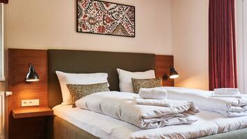 A hotel room with a large bed, two bedside lamps, a wall-mounted artwork, and a red curtain.