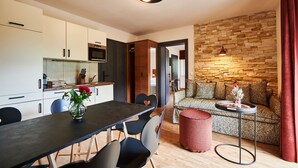 Eine moderne Küche mit weißen Schränken, einer dunklen Arbeitsplatte und einem Essbereich mit schwarzem Tisch und Stühlen.