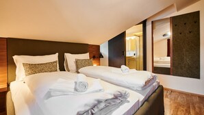 A hotel room with two beds, each with neatly folded towels, a large mirror, and a wooden headboard. - EVI APARTMENTS - Valerie (Kaprun)