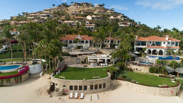 Een resort op een helling met meerdere villa's, een zwembad en weelderige beplanting.