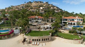 Een resort op een helling met meerdere villa's, een zwembad en weelderige beplanting.