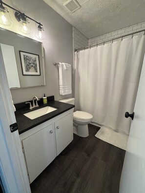 A bathroom with a sink, toilet, and shower curtain.