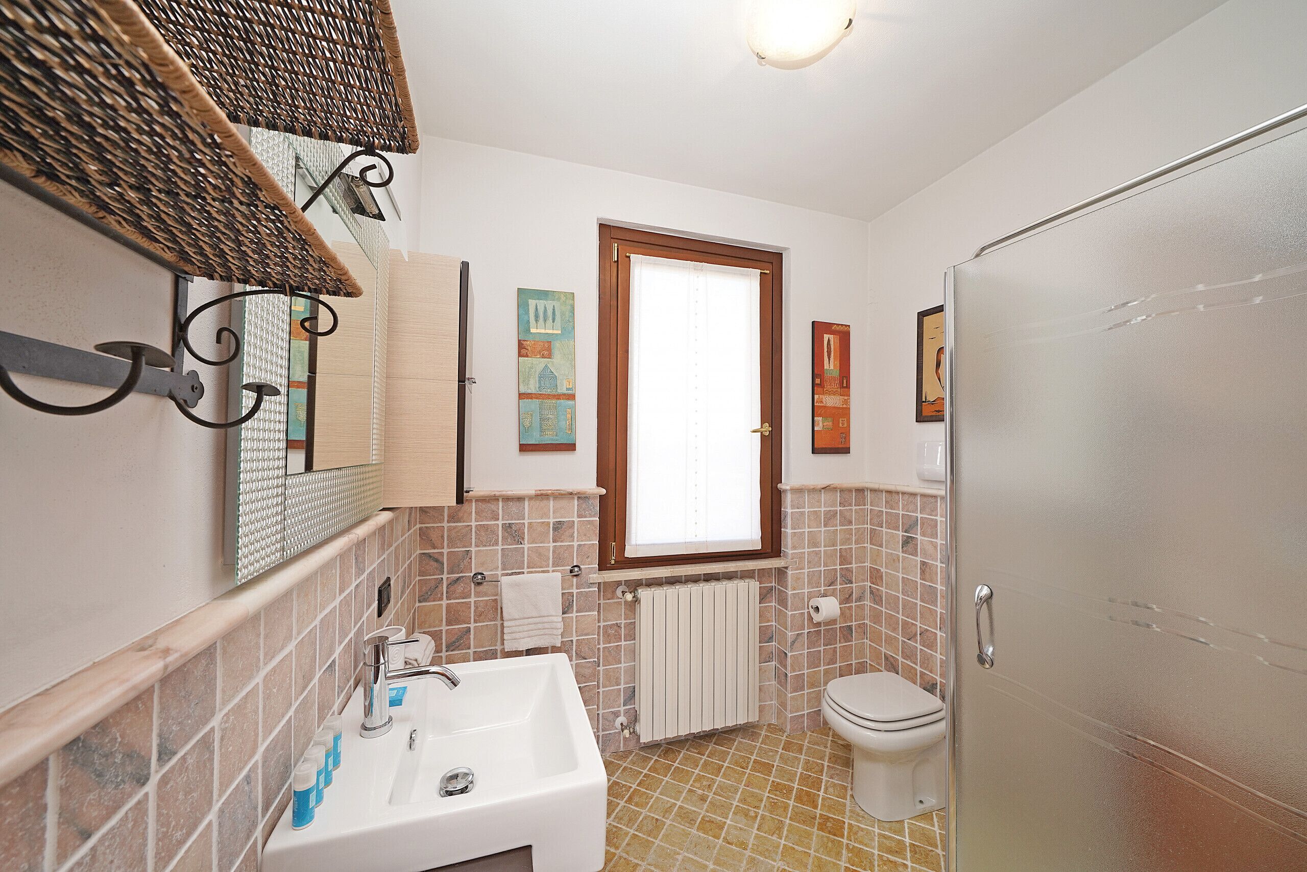 A bathroom with a white sink, toilet, and a window.