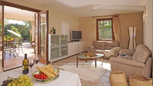 A living room with a sofa, television, and a dining table with food and drinks. - Villa Riai (Moniga del Garda)