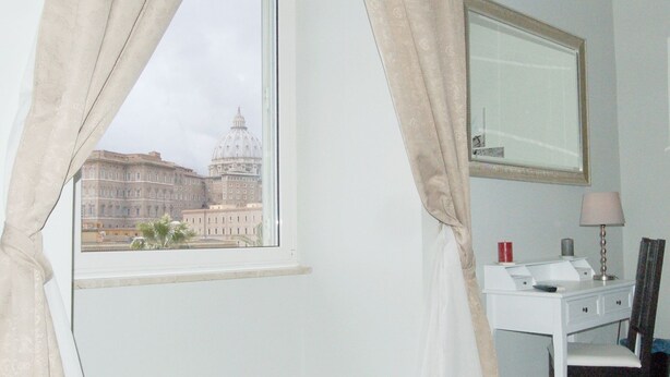 A room with a large window, a desk with a mirror, and a lamp. - Chez Alice Vatican (Rome)