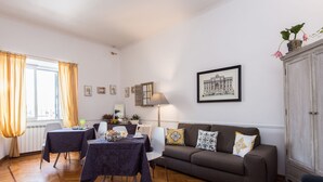 A living room with a sofa, two tables, a lamp, and a framed picture on the wall. - Chez Alice Vatican (Rome)