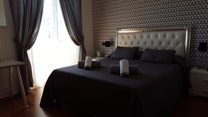 A neatly made double bed with a tufted headboard, two pillows, and rolled towels on the bed. - Chez Alice Vatican (Rome)