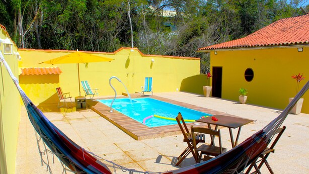 A pool area with a hammock, chairs, and a table.