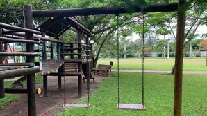 A playground with swings and a wooden climbing structure.
