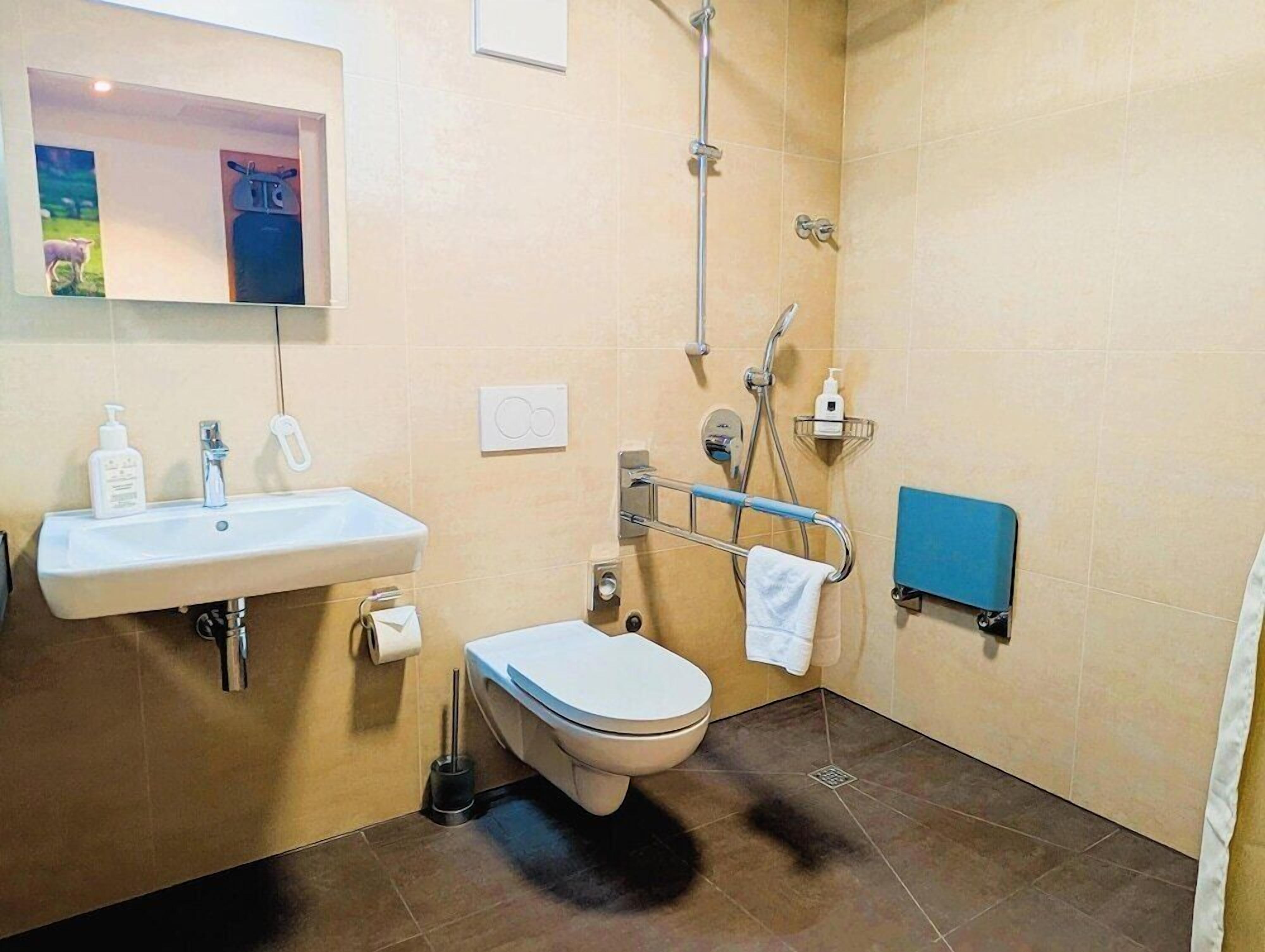 A bathroom with a sink, toilet, shower, and a towel rack.