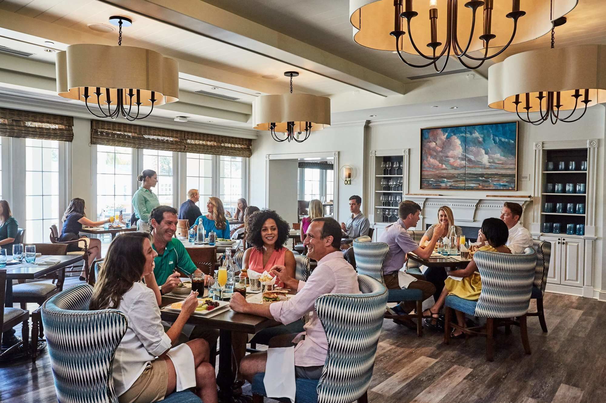 A spacious dining area with high ceilings, chandeliers, and large windows.