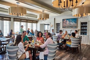 A spacious dining area with high ceilings, chandeliers, and large windows. - Wild Dunes Resort By Destination Hotels (Isle of Palms)